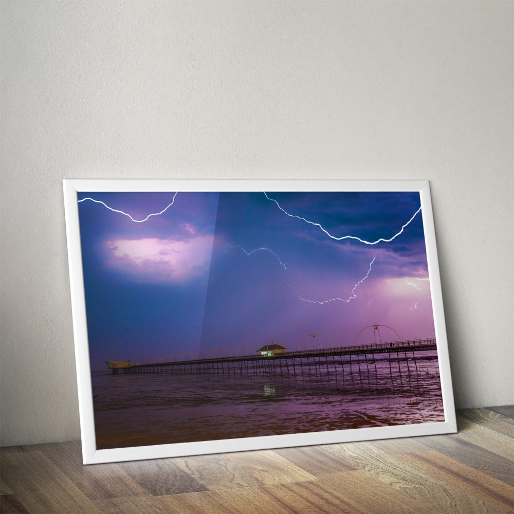 Photo of thunderstorm storm with 3 lightning strikes with a purple and blue hue.